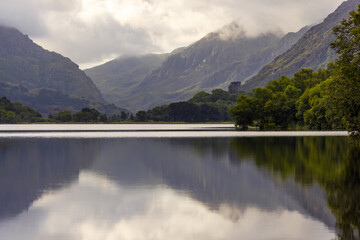 Fototapeta na wymiar Forests, mountains and sundrenched clouds reflected in the calm tranquil water of Llyn Padarn, Llan Beris, Snowdonia, Wales