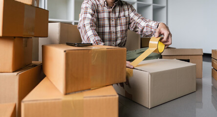Concept young man moving house. Close up hand of man use tape sealing cardboard box