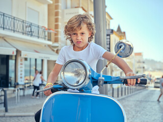 Boy riding moped on street of city