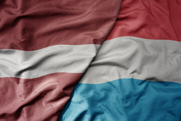 big waving national colorful flag of latvia and national flag of luxembourg .