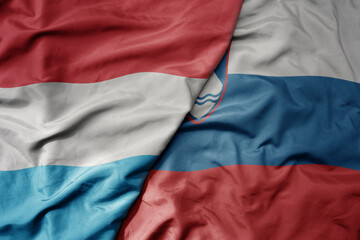 big waving national colorful flag of luxembourg and national flag of slovenia .
