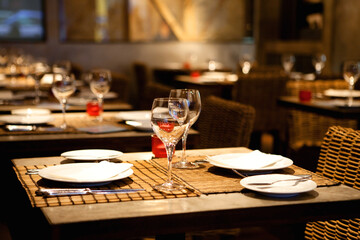 Cozy Restaurant Setting with Rustic Wooden Table Adorned with Plates, Glasses, and Wine: An...