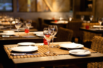 Cozy Restaurant Setting with Rustic Wooden Table Adorned with Plates, Glasses, and Wine: An Invitation to Convivial Gatherings and Culinary Pleasures