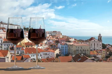 Cercles muraux Couleur saumon Two glasses of red wine on view of the Lisbon old town in Alfama district in Lisbon, Portugal