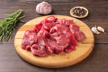 Raw sliced beef or lamb meat, spices, herbs on a wooden background.