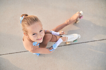 Cheerful girl tying shoelaces on roller skate before training