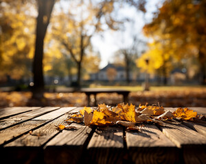 Naklejka na ściany i meble Orange and yellow dry leaves on wooden boards against the background of blurred foliage of trees in a beautiful autumn park