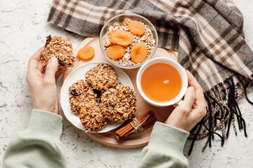 Woman hold cup of tea and cereal homemade cookie, autumn scarf at the background, top view.
