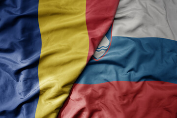big waving national colorful flag of romania and national flag of slovenia .