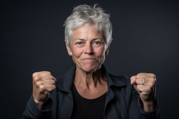 Close-up portrait photography of a tender mature woman gesturing victory against a cool gray background. With generative AI technology