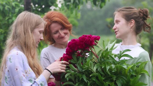 mother with her daughters standing with the peonies bouquet