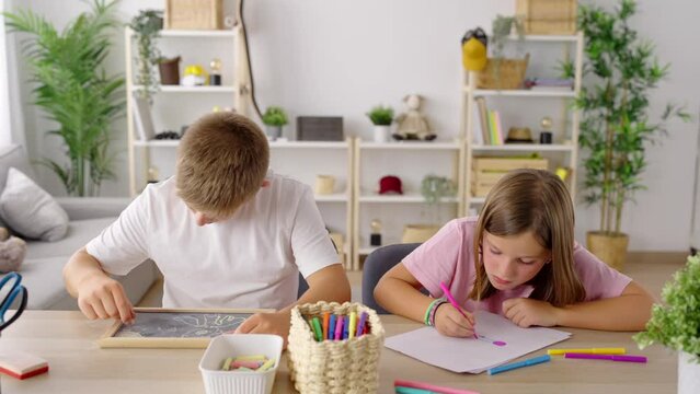 Two preteen children drawing at home together.