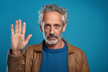 Close-up portrait photography of a tender mature man making a sorry gesture with hands together against a cerulean blue background. With generative AI technology