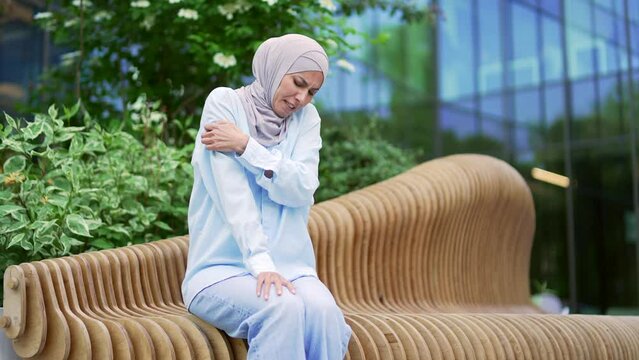 Allergy attack. Itch or pruritus. Muslim female in hijab scratching suffering from allergic reaction or mosquito bite sitting on the street. Woman has scabies or as a result of stress scratch body