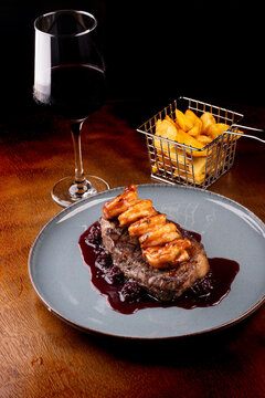 surf and turf close-up with a thick slice of sirloin steak and shrimp with blackberry jam with red wine
