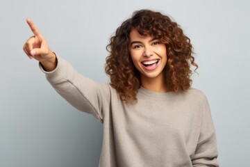 Lifestyle portrait photography of a grinning girl in her 20s raising a finger as if having an idea against a minimalist or empty room background. With generative AI technology