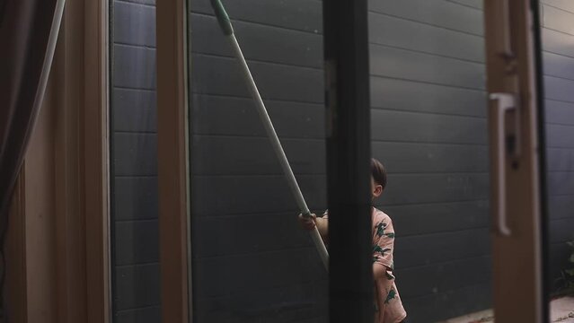 Cleaning little boy washing windows using a squeegee to wash a window. Domestic work and household duties concept. Son help his mom wash window.