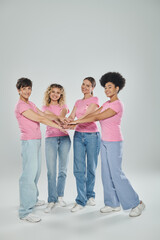 Fototapeta premium happy interracial women different age gathering hands on grey backdrop, breast cancer awareness