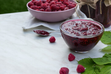 Raspberry jam with berryin glass bowl on light background. Homemade jam with raspberry. Banner, menu, recipe. Side view, place for text.