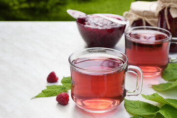 Tea herbal drink from raspberry in glass cups on light background. Side view. Copy space.