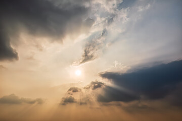 The sun shines through the clouds at sunrise