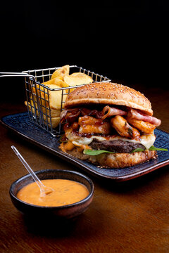 surf and turf burger with shrimp beef burger with basket of fried rustic potatoes and sauce