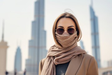 Lifestyle portrait photography of a tender mature woman holding a laptop wearing a protective neck gaiter in front of the burj khalifa in dubai uae. With generative AI technology