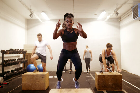 Fit young woman doing box jumps during an exercise class