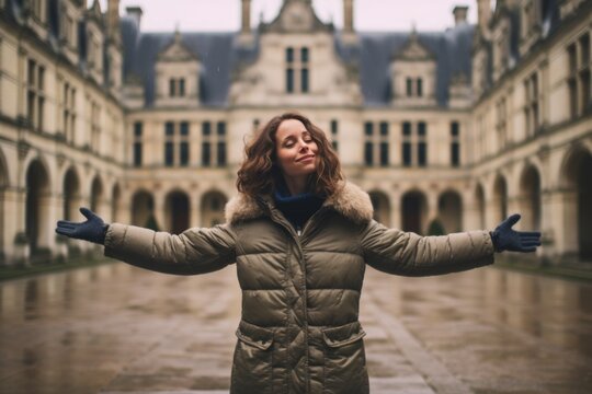 Medium shot portrait photography of a tender girl in her 30s raising arms sporting a quilted insulated jacket at the chateau de chambord in chambord france. With generative AI technology