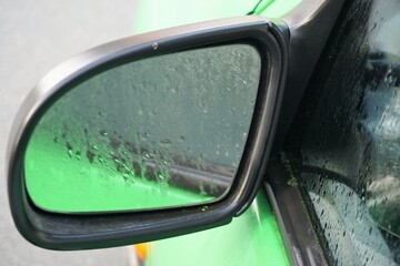 Autospiegel mit Wassermuster auf Glas bei Regen am Morgen im Herbst