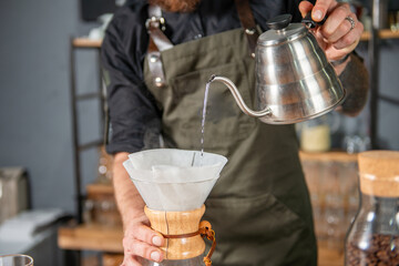 Skillful barista meticulously preparing a Chemex coffee, demonstrating the art of pour-over brewing 