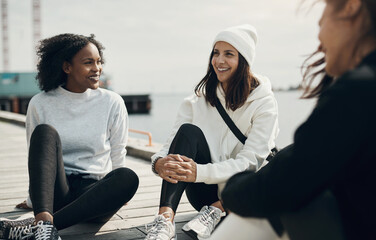 Diverse smiling women talking on a dock after a run