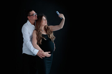 A young couple of parents-to-be taking selfies against