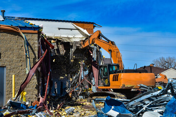 Heavy equipment works to remove an existing commercial building to make room a new business in busy urban area.
