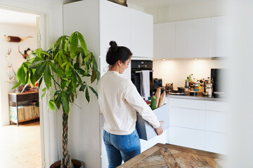 Woman carrying groceries in her kitchen