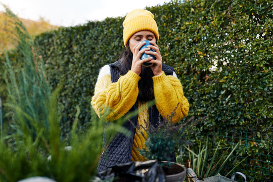 Woman drinking some coffee while gardening