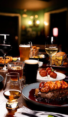 dinner banquet with surf and turf close-up of steak and prawns with finger food portions on a table set with starters beers wines drinks in pub