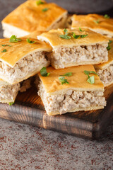 Spicy breakfast casserole of minced Italian sausages with cream cheese close-up on a wooden board on the table. Vertical