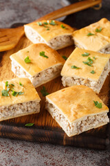 Homemade casserole of minced Italian sausages with cream cheese close-up on a wooden board on the table. Vertical