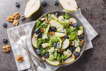 Fresh diet salad with blueberries, lettuce, gorgonzola cheese, walnuts and pear close-up in a plate on the table. horizontal top view from above