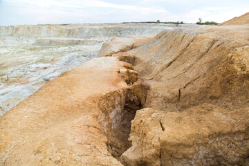 A deep crack in the mountain crack in the clay earth. Abandoned clay quarry.