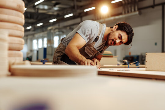Young carpenter making wood furniture while working in joinery