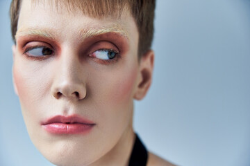 close up, androgynous person with makeup, grey backdrop, beauty and visage, queer, portrait