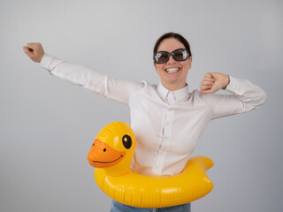 Caucasian woman in a white shirt dreaming of a vacation and wearing sunglasses and an inflatable duck. 