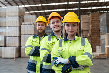 Portrait of group of man and woman workers working at wood pallet factory. Team carpenter in uniform with helmet safety smile and standing arms crossed look at camera in wood warehouse.