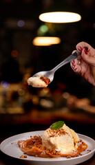 spoon showing tasting banoffee dessert with banana dulce de leche vanilla ice cream and crushed...