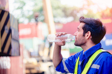 Engineer or worker drinking bottle of water in engineering or construction site after long work hours.