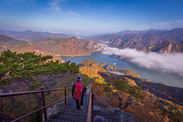 tourist with backpack admiring landscape in Autumn In the morning, a sea of ​​mist flows...