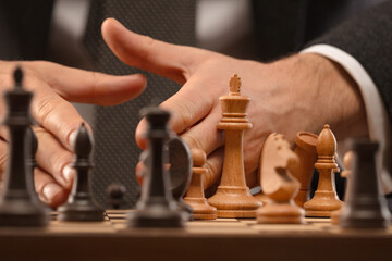 The male chess player's hand throws pieces off the chessboard. Shallow depth of field