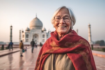 Naklejka premium Lifestyle portrait photography of a happy mature woman wearing a cozy sweater in front of the taj mahal in agra india. With generative AI technology